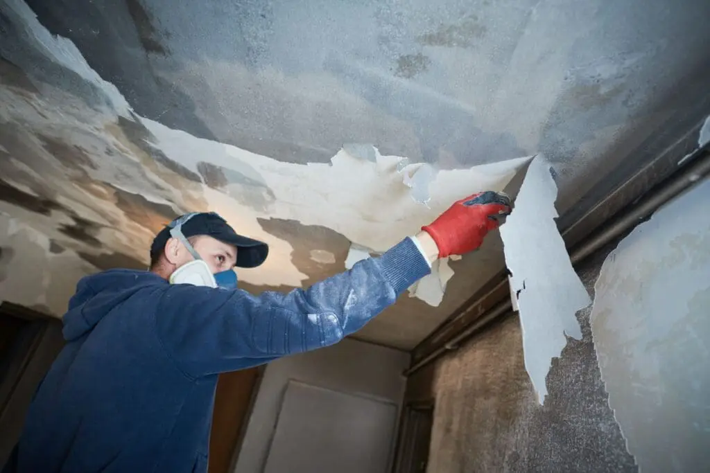 worker scrapping burned ceiling